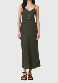 Mörkgrön ärmlös maxiklänning med en figursydd silhuett. Har smala band och ett mjukt, lätt tyg. Kombination med svarta sandaler.