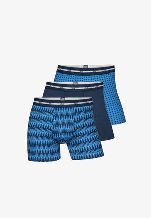 Three pairs of blue boxer shorts featuring various patterns: one with zigzag, one with polka dots, and one solid dark blue, all with elastic waistbands.