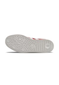 White sneaker sole featuring a textured pattern with circular and linear designs, accented by red stripes along the sides.