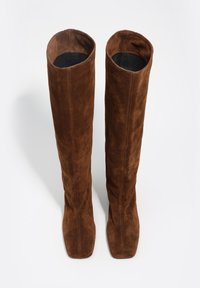 Brązowe zamszowe kozaki za kolano z zaokrąglonym noskiem, gładką fakturą i pionowymi szwami, wyposażone w miękką, nieusztowioną cholewkę.