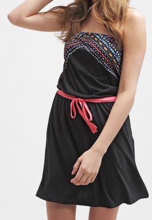 Sort stropløs kjole med en farverig mønstret top og et lyserødt stofbælte. Designet er løstsiddende med en flæse-silhuet.