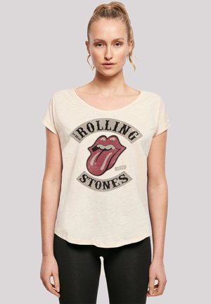 Cream-colored t-shirt with short sleeves, featuring a distressed red tongue logo and "The Rolling Stones" text in black. Soft, relaxed fit.