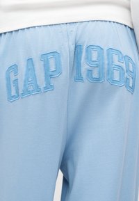 Φωτεινά γαλάζια φόρμα με ανάγλυφο κέντημα σε ανοιχτό γαλάζιο χρώμα με το κείμενο "GAP 1969" στην εμπρόσθια ζώνη μέσης.