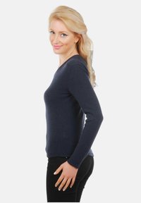 Haut à manches longues de couleur marine au design ajusté, fabriqué en tissu doux avec une texture lisse. Présente un décolleté en V et des manches ajustées.