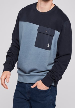 Marineblauer und hellblauer Sweatshirt mit langen Ärmeln, das über eine Brusttasche, einen runden Halsausschnitt und ein kleines Logo auf der Tasche verfügt. Aus Baumwollmischung.