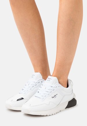 Bílé sportovní boty z kůže a syntetických materiálů, s texturovaným povrchem, šněrováním a černým akcentem na patě.