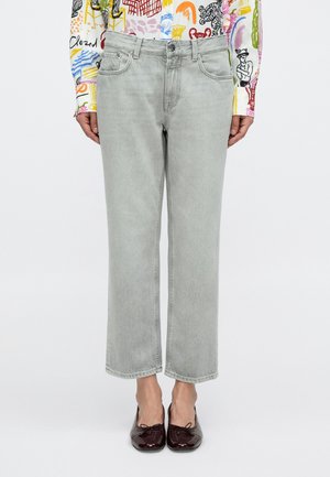 Jasnoszare jeansy z denimu o prostym kroju, z pięcioma kieszeniami i minimalistycznymi przeszyciami, w połączeniu z bordowymi balerinami.