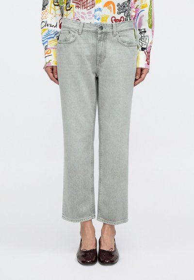 Jean en denim gris clair à coupe droite, cinq poches, détails de couture minimalistes, associé à des ballerines bordeaux.