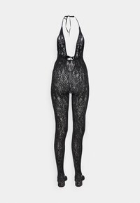 Svart spetsbodysuit med djup V-ringning, halterneck-uppknutningar och långben. Har intrikata blommönster och en kroppsnära design.