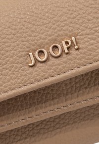 Beige leren portefeuille met textuur en een gouden "JOOP!" logo. Inclusief horizontale stiksels en een gladde afwerking.
