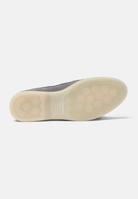 Suela de zapato gris con fondo de goma beige que presenta patrones de agarre circulares y el nombre de la marca "Scarosso" grabado en el centro.