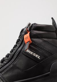 Czarne skórzane wysokie sneakersy z bocznym zamkiem błyskawicznym, teksturowanym wykończeniem, pomarańczową metką z oznaczeniem "DIESEL 1978" oraz sznurowanym designem.