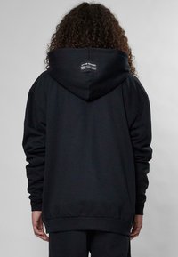 Felpa nera oversize con cappuccio grande, polsini e orlo a costine. Presenta un'etichetta rettangolare sul retro vicino al collo. Tessuto morbido.