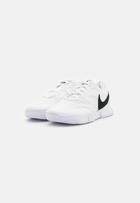 Pantofi sport albi cu un superior texturat, având un logo negru, o zonă de șireturi texturată și o talpă de suport cu un model de crampoane.