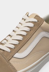 Μπεζ και καμηλό αθλητικό παπούτσι χαμηλού πάτου με λευκά κορδόνια και λευκή δερμάτινη πλαϊνή ρίγα σε λευκή ελαστική σόλα.