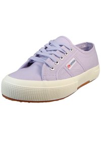 Light purple canvas sneaker with white rubber sole, round toe, and flat laces. Features metal eyelets and a small red logo tag on the side.