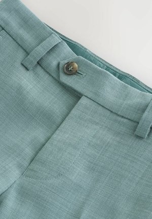 Pantalones de lino azul claro con frente plano, cierre de un solo botón y trabillas para el cinturón. La textura parece tejida y suave.