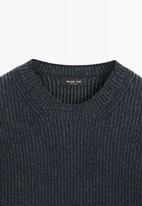 Maglione a coste di un grigio scuro con scollatura rotonda e una texture sottile. L'etichetta del brand è visibile all'interno del colletto. Design semplice e strutturato.