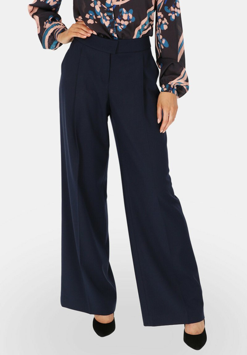 Granatowe spodnie szerokie o dopasowanym kroju, z wysokim pasem i gładką fakturą materiału. Wykończone wyraźnymi fałdami z przodu.