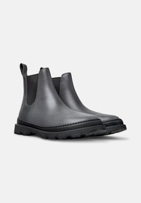 Botas Chelsea de cuero negro con paneles laterales elásticos, tiradores y suelas de goma texturizada. Punta redondeada y detalle de costura en contraste.