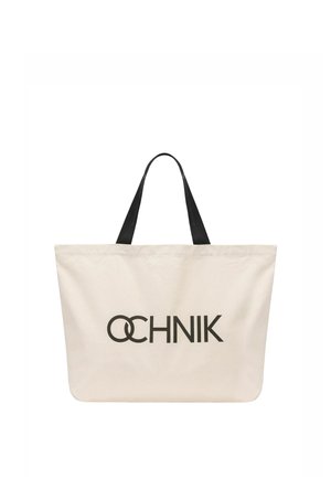 Kremowa torba na ramię z czarnymi rączkami i wyraźnym czarnym logo "OCHNIK" nadrukowanym na środku z przodu.