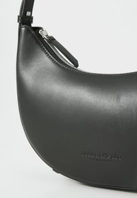 Borsa a mano in pelle nera con una forma curvata, dotata di chiusura superiore con zip, logo impresso e superficie liscia.