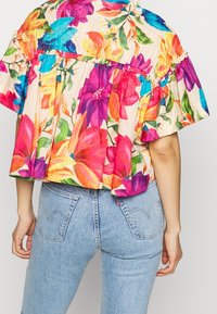 Bluse med blomsterprint i livlige farver som pink, orange og blå, med en afslappet form og rynkede ærmer. Lavet af letvægtsstof.