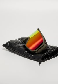 Skibriller med reflekterende rød-orange linse, olivengrøn ramme og sort strop, der hviler på en sort polstret opbevaringspose med lynlås.