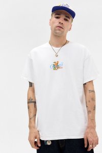 Hvid bomulds T-shirt med rund hals, prydet med farverige grafikker af frugt og teksten "Orejii" i midten. Mørke denim jeans og synlige tatoveringer.