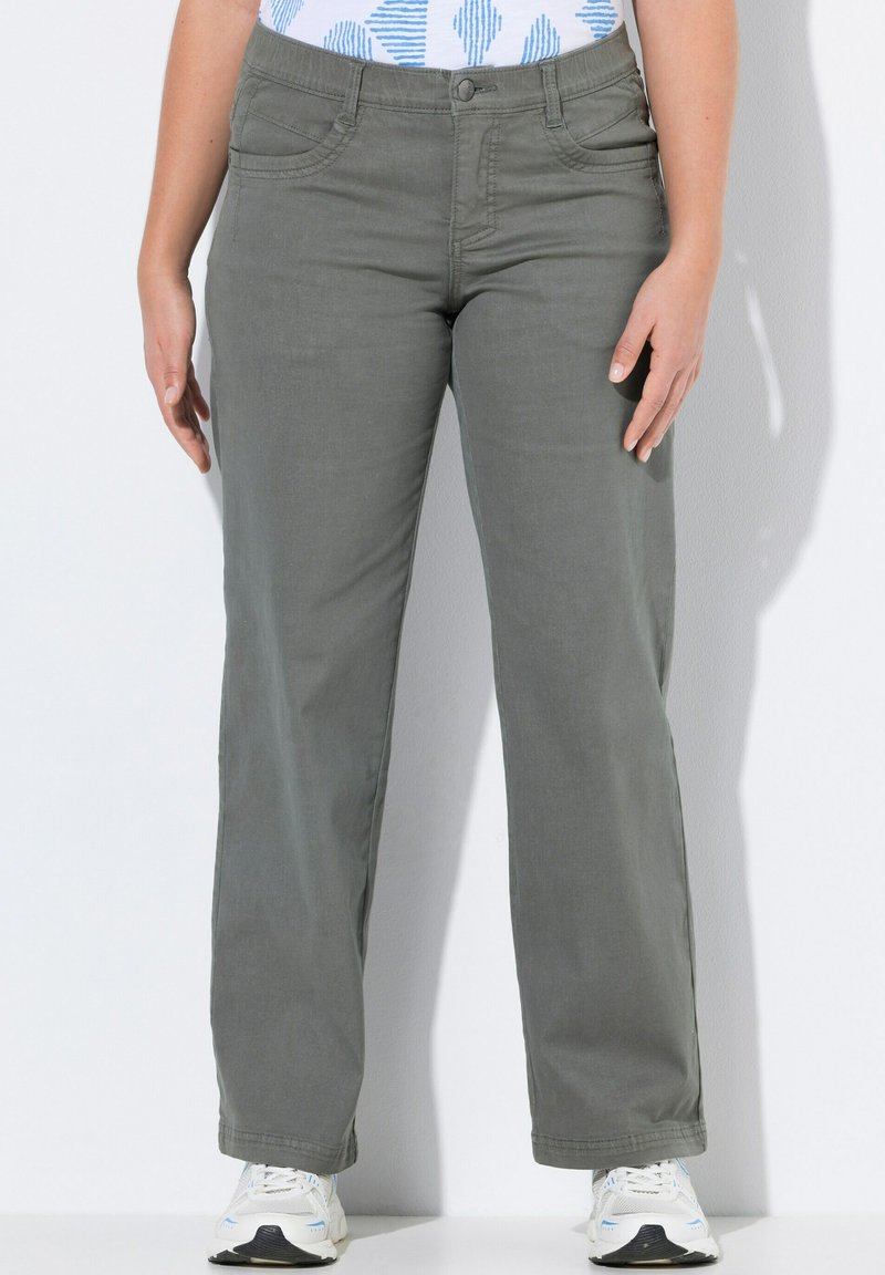 Pantalons en coton mélangé gris avec une coupe droite, dotés de poches avant et d'une fermeture à bouton, associés à des baskets blanches.