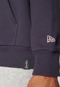 Marineblå sweatshirt med ribbede manchetter, lomme foran og broderet Yankees-logo i pink på ærmet. Blødt bomuldsblandingsmateriale.