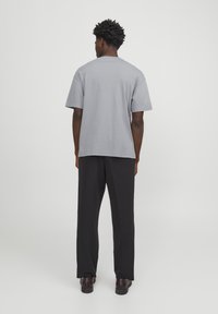 Short-sleeved gray t-shirt, relaxed fit, paired with black trousers. The shirt features a round neckline and casual hemline.
