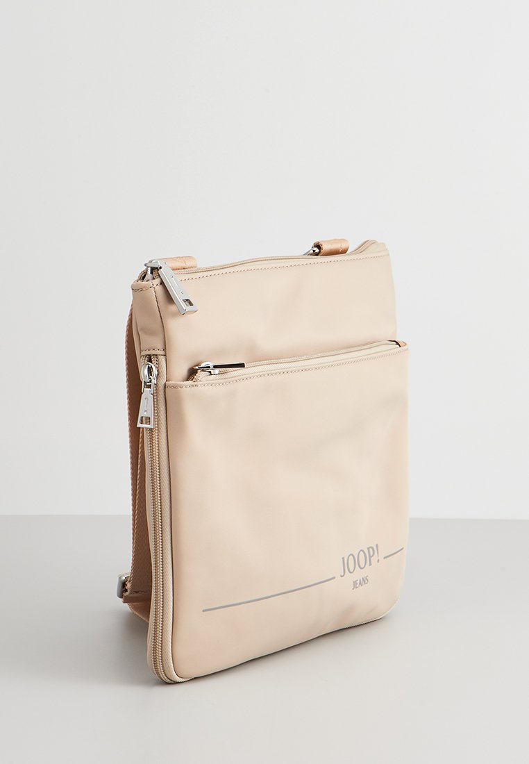 Beige synthetische Umhängetasche mit zwei Reißverschlussfächern, mit einer glatten Textur und dem aufgedruckten Logo "JOOP! JEANS" am Boden.