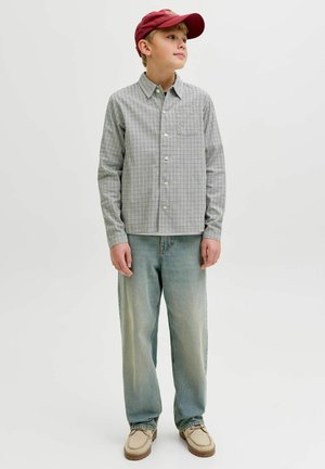 Camicia a quadri con bottoni in grigio e bianco, jeans di denim leggero a taglio largo, mocassini beige e berretto da baseball color bordeaux.