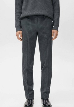Pantalones a rayas grises con un corte ajustado, hechos de una tela texturizada, que cuentan con bolsillos delanteros y una cintura suave. Zapatos negros complementan el conjunto.