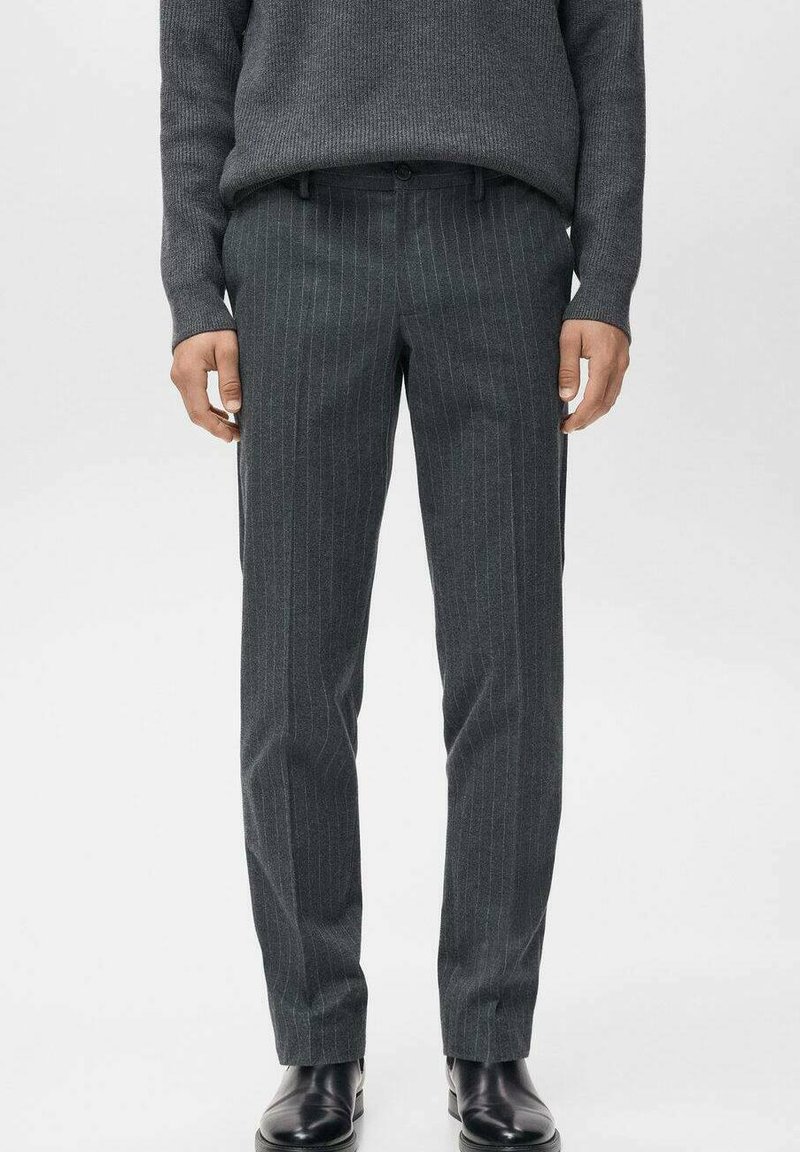 Pantaloni grigi a righe sottili con una vestibilità su misura, realizzati in un tessuto testurizzato, dotati di tasche frontali e una cintura liscia. Scarpe nere completano il look.
