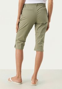 Shorts de cargo verde măsliniu cu un design ajustat, ajungând până la mijlocul gambei, având buzunare la spate și fante laterale. Fabricat dintr-un amestec ușor de bumbac.
