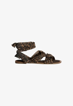 Sandalias planas de estampado de leopardo con correas de tela, que presentan acentos anudados y diseño de punta abierta. La suela es de color marrón claro con una textura suave.