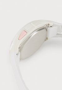 Montre connectée blanche avec un dos en argent, dotée d'un bouton rose, d'accents texturés et d'un bracelet lisse et courbé.