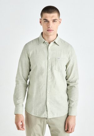 Light green long-sleeve shirt made of textured fabric. Features a button-down collar and a chest pocket with a small brand label.