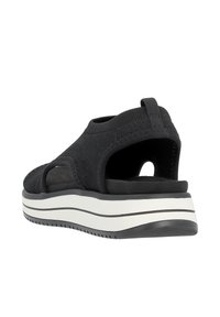 Schwarze Sandale mit gestricktem Obermaterial, offenem Rücken und seitlichen Ausschnitten. Verfügt über eine dicke weiße Zwischensohle mit schwarzen Streifen und einer strukturierten Sohle für besseren Halt.