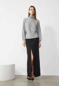 Hall turtleneck, pikad varrukad, musta maxi seeliku kõrge lõhiku ja mustade kontsakingadega. Siledad tekstuurid.