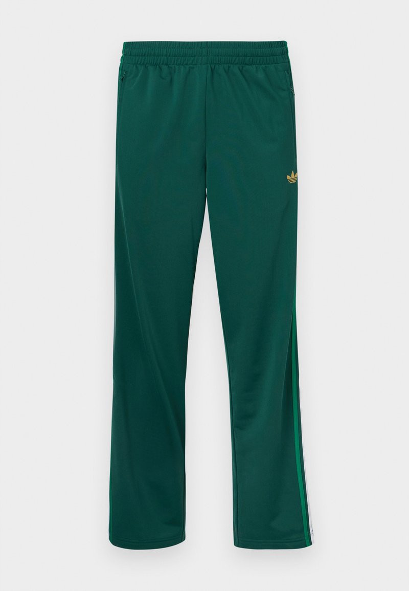 Pantalon de sport vert avec une ceinture élastique, présentant des bandes latérales et un petit logo doré sur le haut à gauche. Texture lisse.
