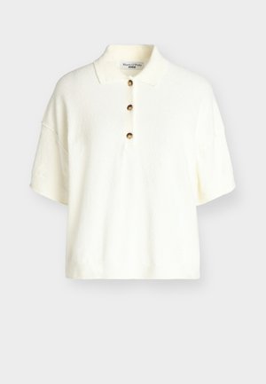 Biały sweter typu polo z krótkim rękawem, trzema brązowymi guzikami i małym kołnierzykiem, prezentowany na jednolitym tle.