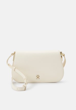 Skórzana torebka na ramię w kolorze kremowym z regulowanym paskiem i małym złotym emblematem logo na przedniej klapie zapięcia.