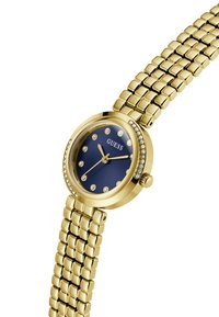 Orologio da polso Guess color oro con quadrante blu, marker delle ore in cristallo, accenti in cristallo sulla ghiera e bracciale in metallo con maglie.
