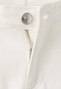 Material din denim alb, prevăzut cu un nasture metalic argintiu și fermoar. Cusăturile sunt subtile, cu o textură netedă și un finisaj curat.