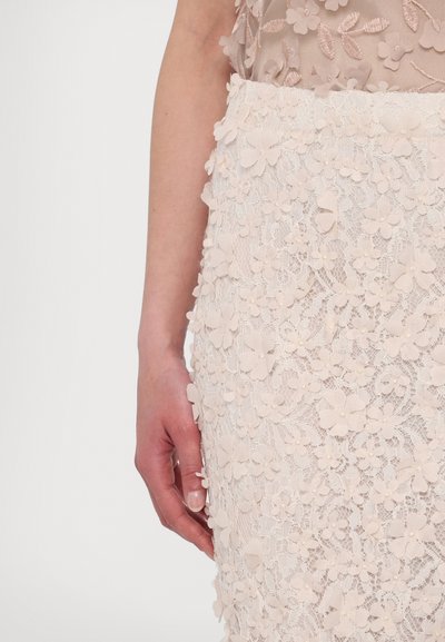 Lace rok in lichtroze met bloemversieringen. Bevat complexe patronen en texturen, die kleine bloemen en delicate details benadrukken.