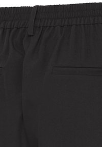Pantalon noir avec taille élastique, texture lisse, et deux poches arrière. Design simple sans attaches ni ornements visibles.