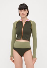 Top corto a maniche lunghe verde oliva con accenti rosa e arancione, abbinato a slip bikini a vita alta nei colori e nel design coordinati.